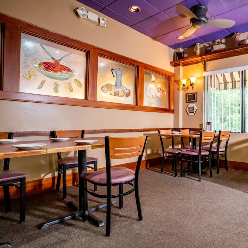Interior of Lido's Restaurant with tables, chairs, and Italian-themed stained-glass windows.