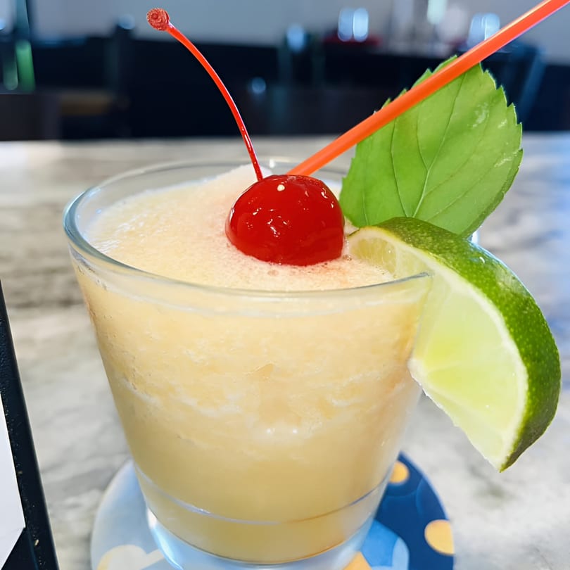 A frozen cocktail with a cherry, lime, and mint leaf garnish, served at Lido's Restaurant.